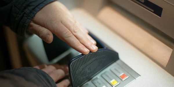 A person shielding the keypad while entering an ATM PIN